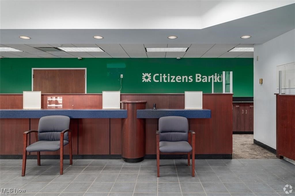 Bank interior with a wood teller counter, two chairs, and Citizens Bank lettering on a green wall.