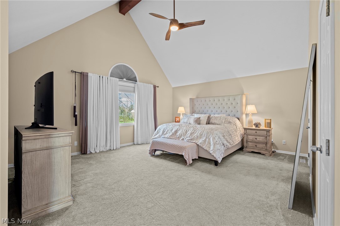 Bedroom with a vaulted ceiling, arched window, and upholstered bed.