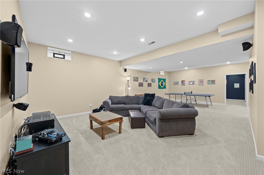 Furnished recreation room with a gray sectional, wall-mounted television, and ping-pong table.