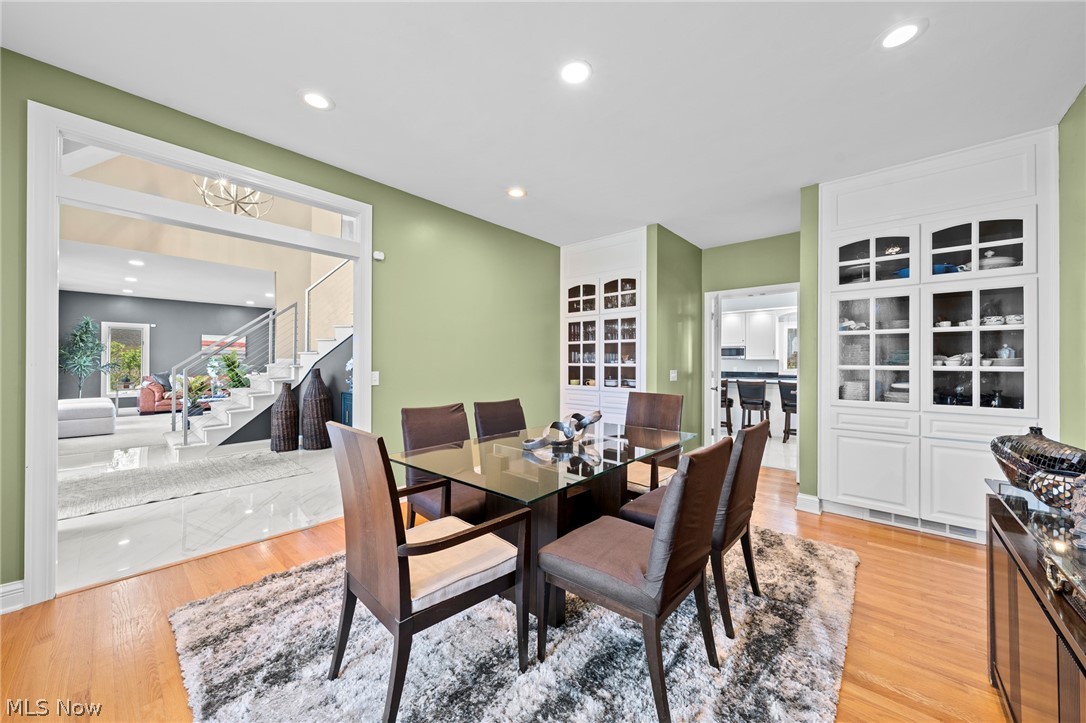 Dining room with a glass-top table, sage-green walls, and built-in display cabinets.
