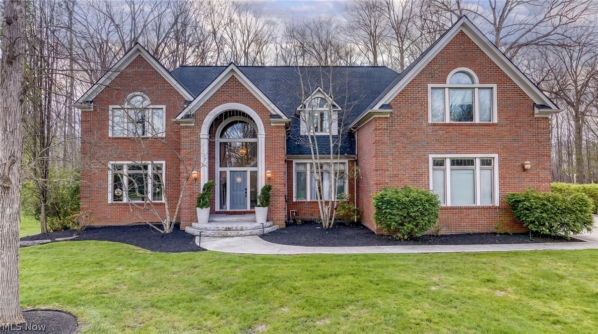 Red-brick home with a tall arched entry, blue front door, and green lawn.