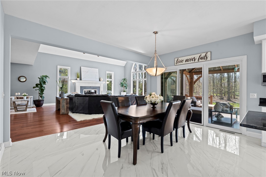 Dining area with a dark wood table, glossy tile floors, and sliding doors to a wooded backyard.