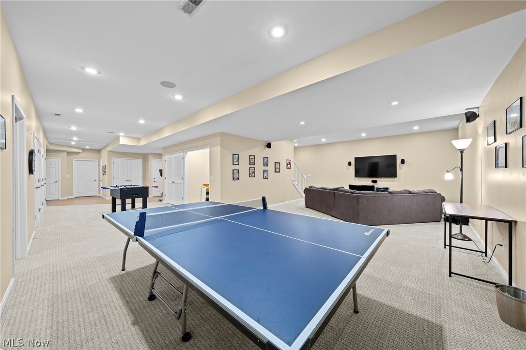Recreation room with a blue ping-pong table, foosball table, and TV seating area.