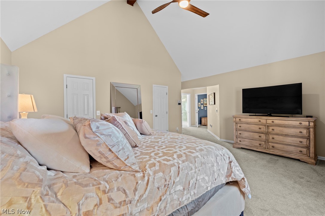 Furnished bedroom with a vaulted ceiling, geometric bedding, and a television on a wooden dresser.