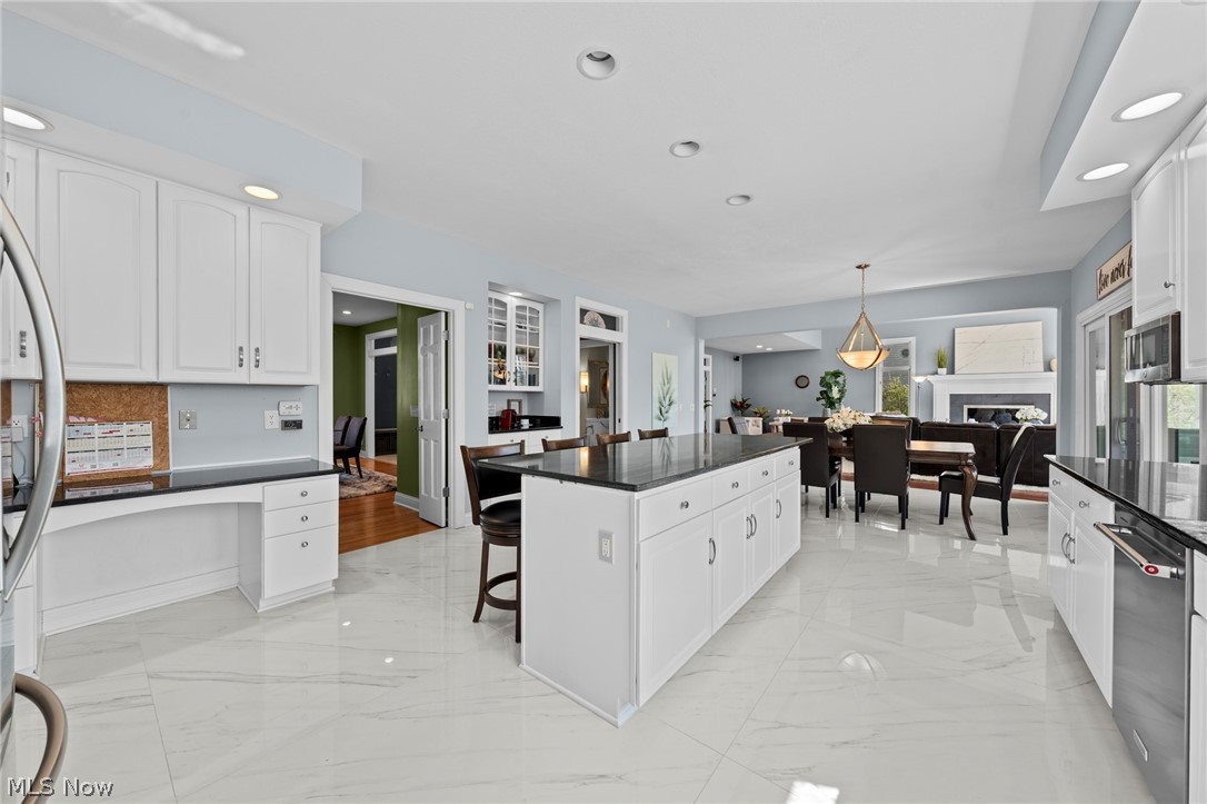 Open kitchen with a large dark-countertop island, white cabinetry, and glossy marble-look floors.
