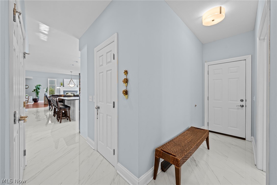 Entry foyer with pale blue walls, glossy tile floors, and a woven bench.