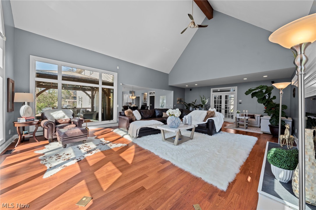 Living room with vaulted ceilings, hardwood floors, and large windows overlooking a covered patio.