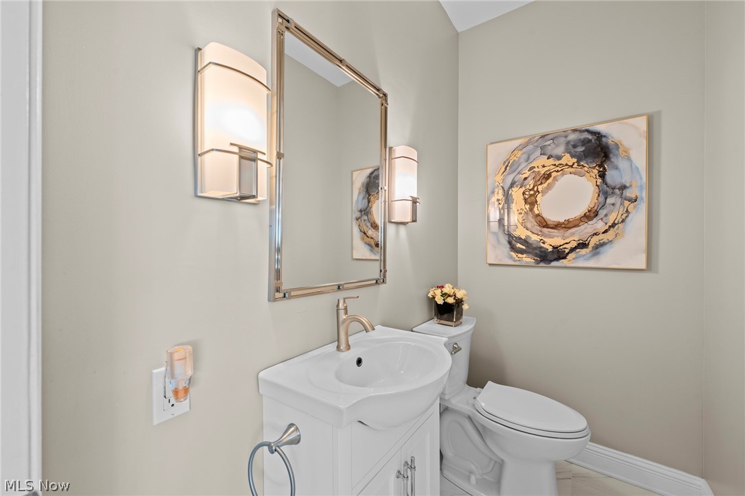 Bathroom with a white vanity and toilet, tall framed mirror, and abstract wall art.