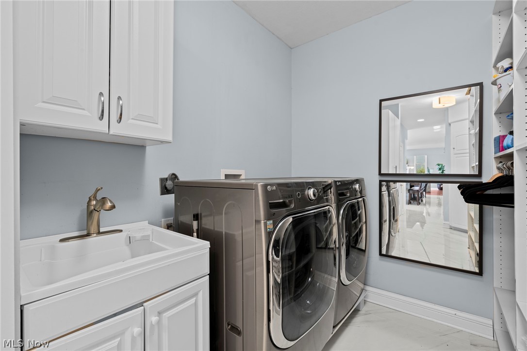 Laundry room with a utility sink, stainless steel washer and dryer, and open shelving.