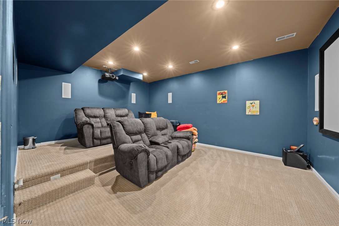Home theater with tiered carpeted seating, gray recliners, blue walls, and a ceiling-mounted projector.