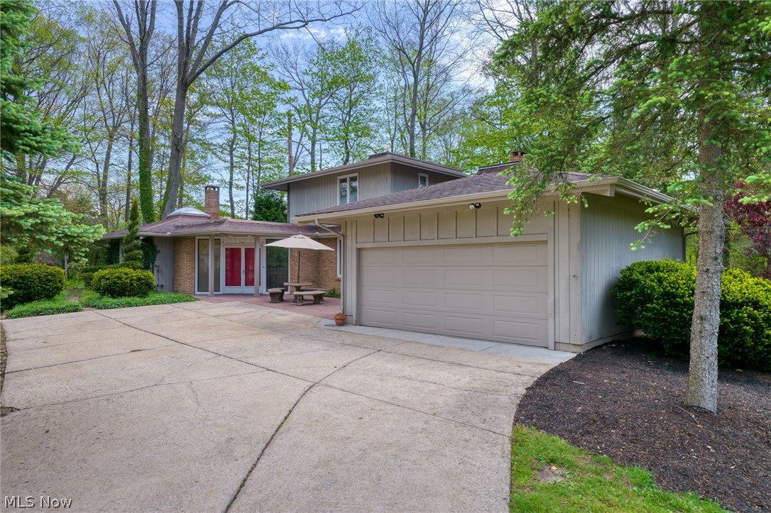 Two-story home with a wide driveway, double garage, and mature trees.