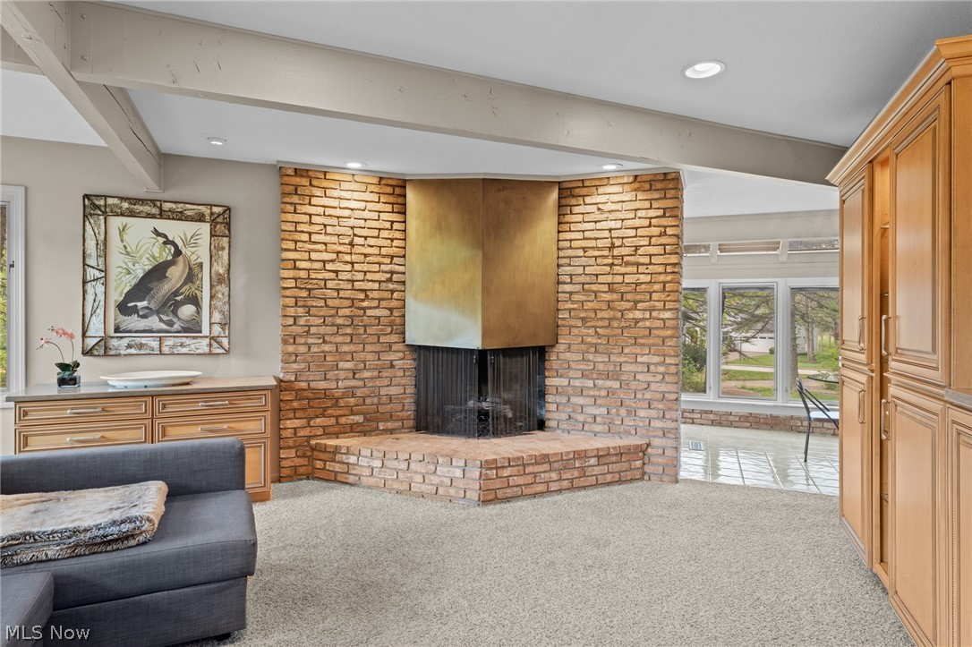Living room with a large brick fireplace, wood cabinetry, and an adjoining sunroom.