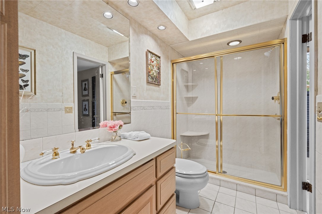 Bathroom with a wood vanity, gold faucets, and a glass shower with gold trim.