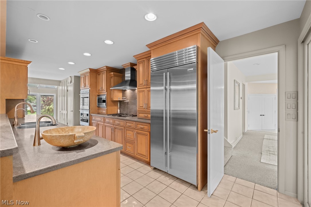 Kitchen with wood cabinetry, stainless steel appliances, and a stone vessel sink on the island.