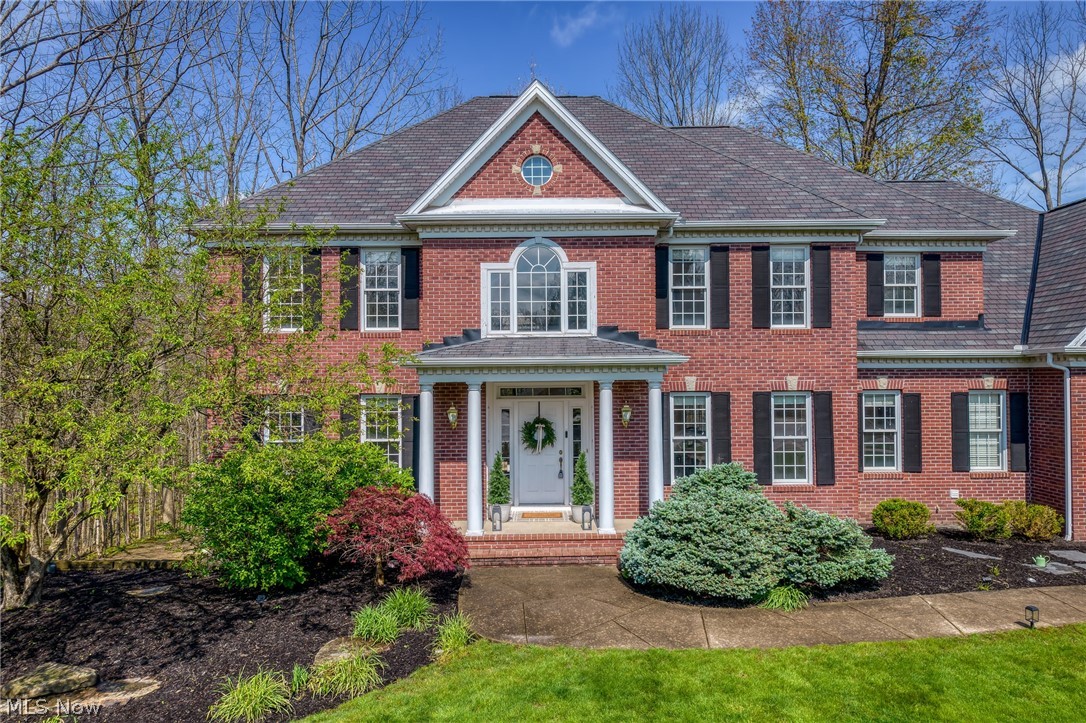 Red brick two-story home with a columned entry porch and landscaped front garden.