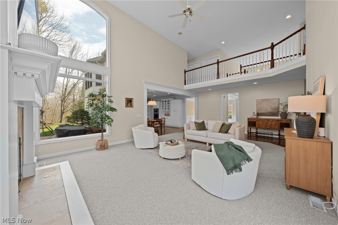 Furnished two-story living room with vaulted ceiling, loft railing, and oversized windows.