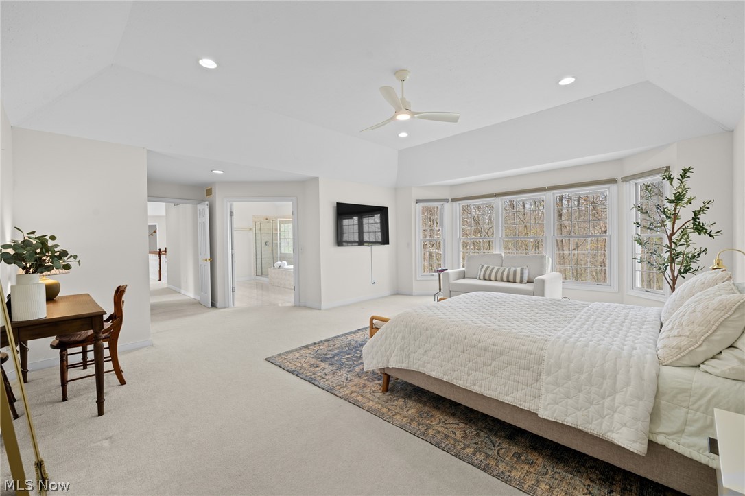 Bright bedroom with a large bed, window-side sitting area, and bathroom visible through the doorway.