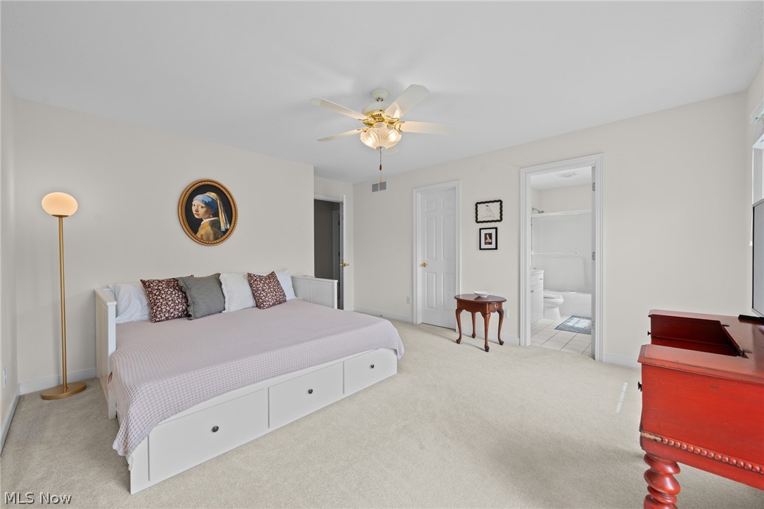 Bedroom with a white storage bed, ceiling fan, and open doorway to an en-suite bathroom.
