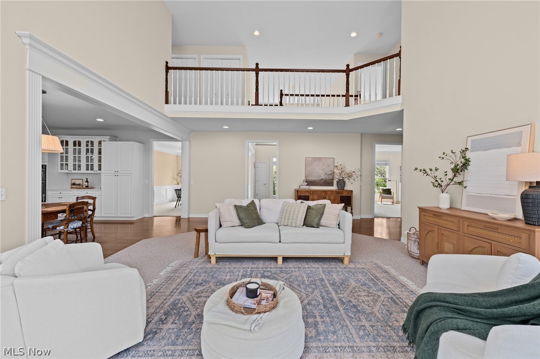 Two-story living room with white sofas, a patterned rug, and an upper-level gallery overlooking the space.