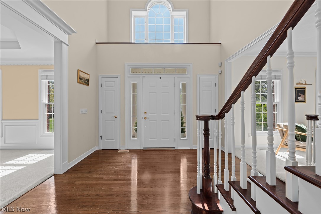 Two-story foyer with hardwood floors, an arched window above the front door, and a dark wood staircase.