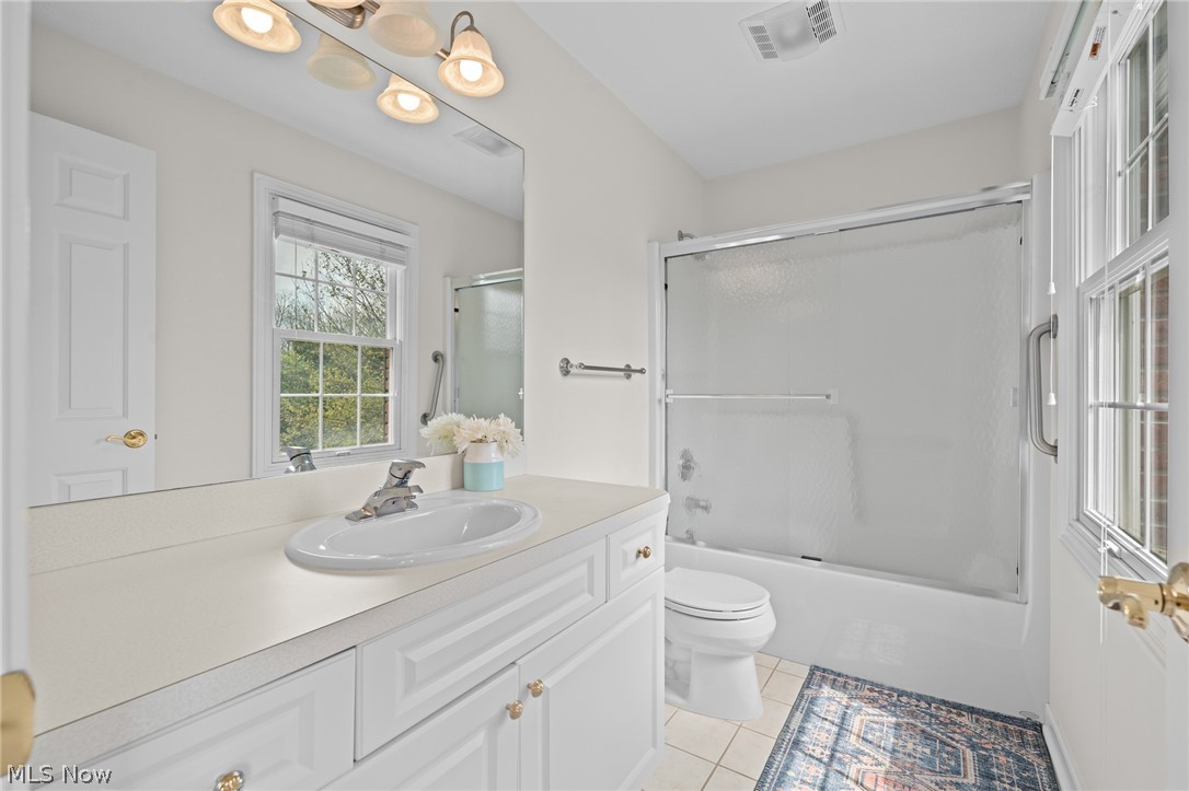 Bathroom with white vanity, large mirror, window, and tub-shower enclosure.