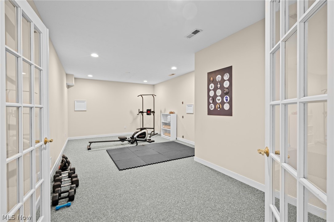 Home gym with a rowing machine, dumbbells, and a large black exercise mat.
