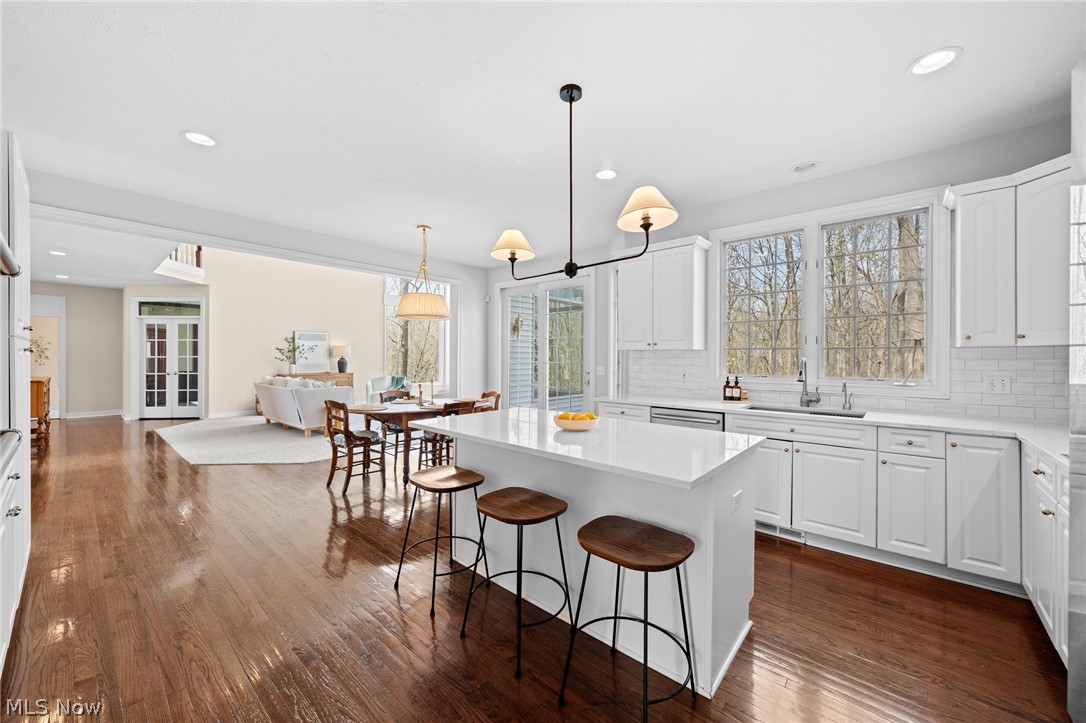 Open-plan kitchen with a large white island and dark hardwood floors adjoining the dining and living areas.