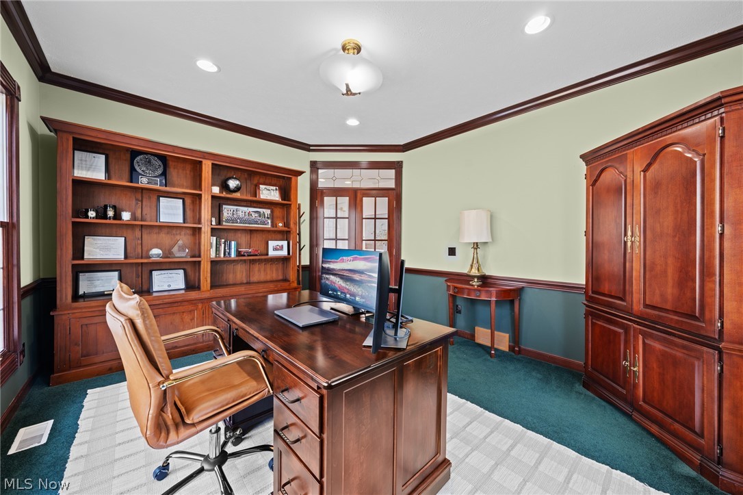 Wood-paneled home office with built-in bookshelves, a large desk, and a leather chair.