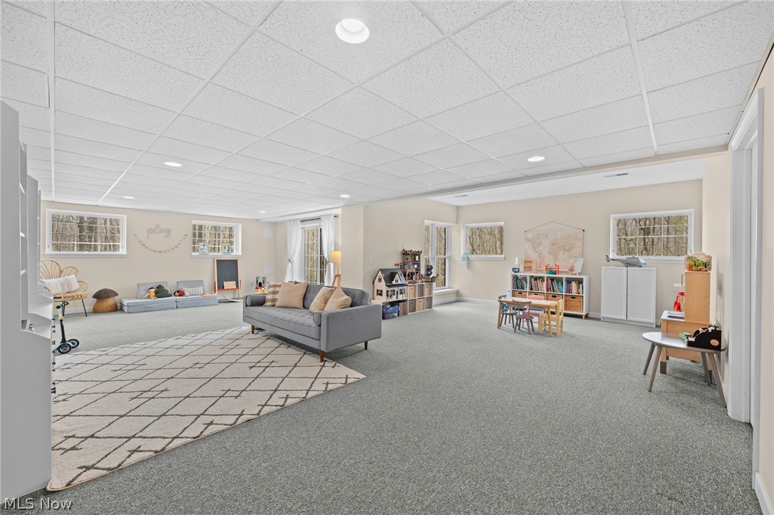 Spacious playroom with a gray sofa, patterned rug, children’s toys, and a small activity table.