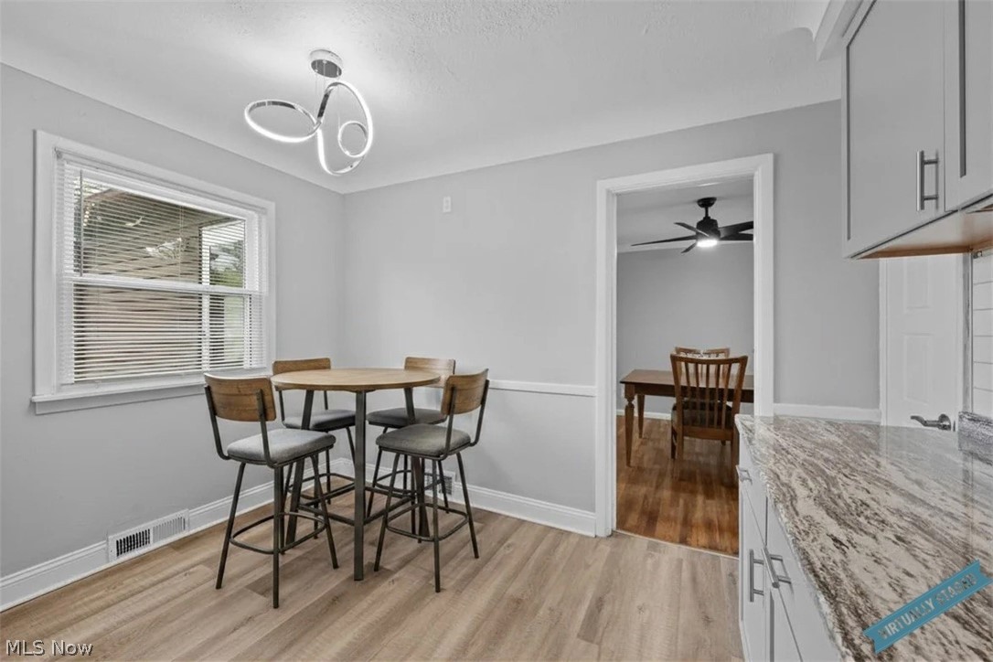 Kitchen dining nook with a round table, four chairs, granite countertop, and doorway to a dining room.