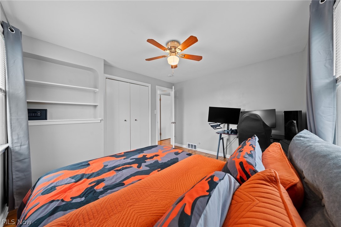 Bedroom with bold orange and navy bedding, built-in shelves, and a computer desk.
