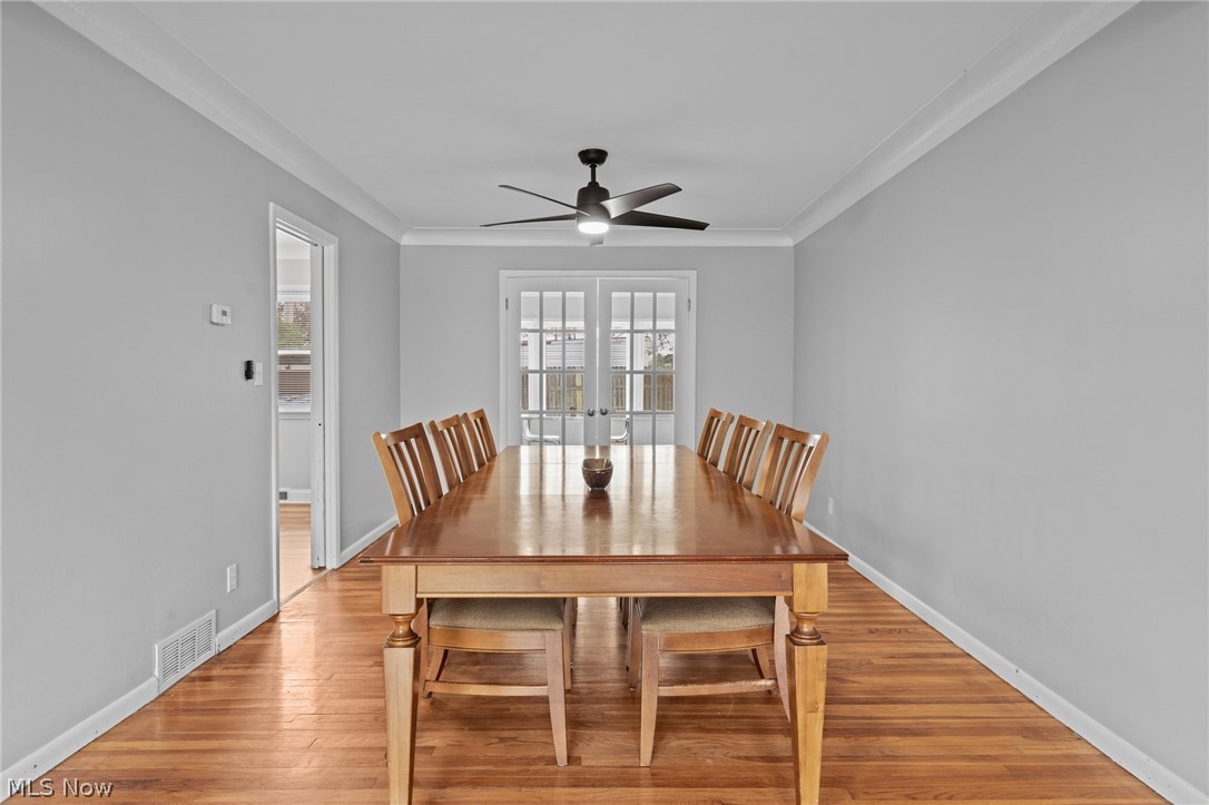 Dining room with a long wooden table, hardwood floors, and French doors.