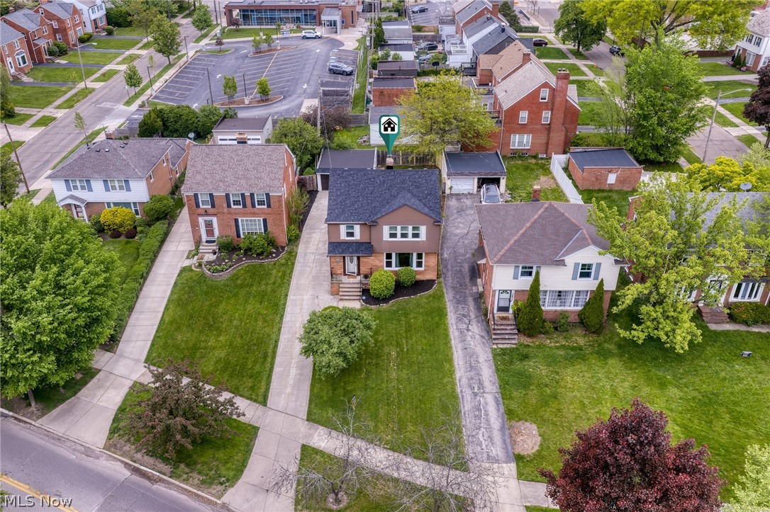 Aerial view of a brown two-story home with a front lawn and driveway, marked by a location pin.