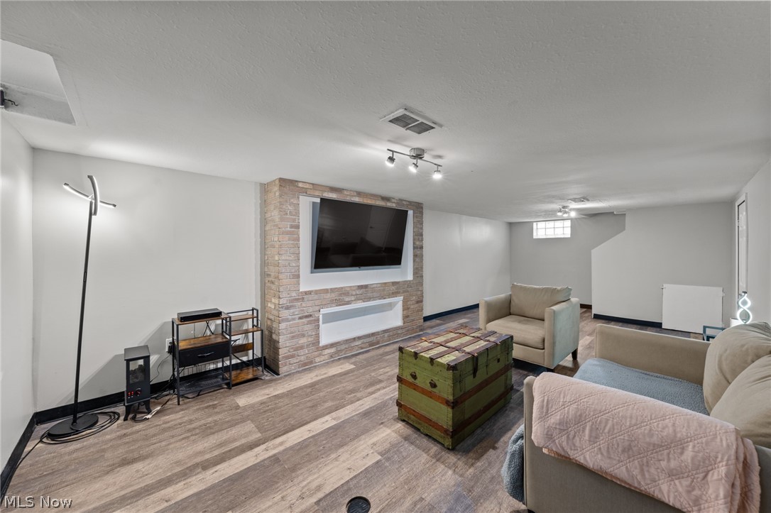 Furnished basement living room with a brick TV surround and green trunk coffee table.