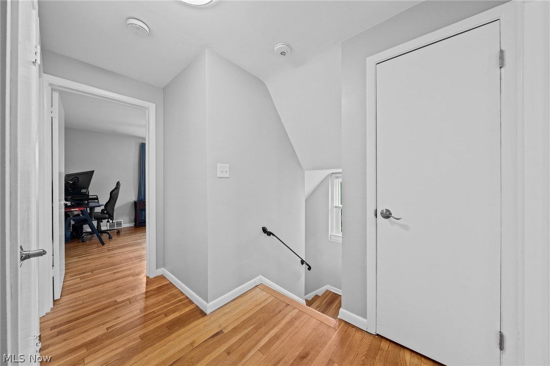 Upstairs landing with hardwood floors, a stairway, and an office visible through the doorway.