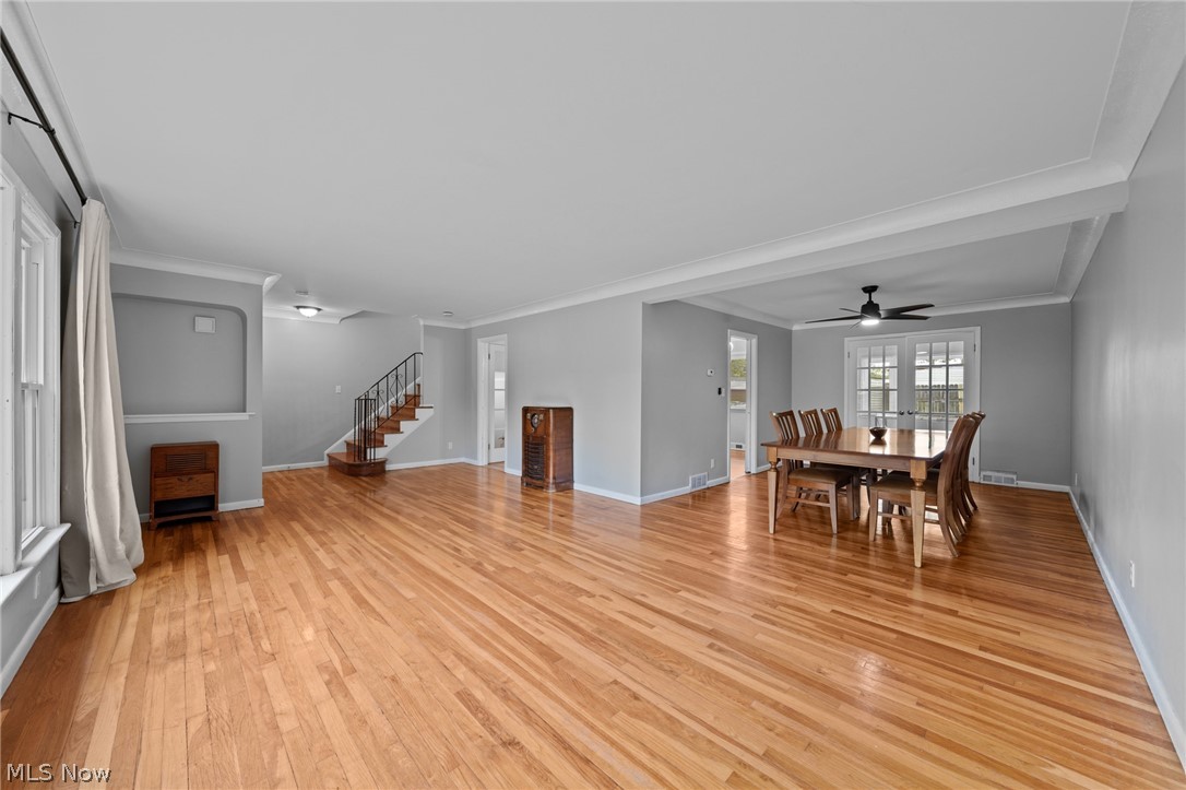 Living and dining room with hardwood floors, gray walls, and a dining table by glass doors.