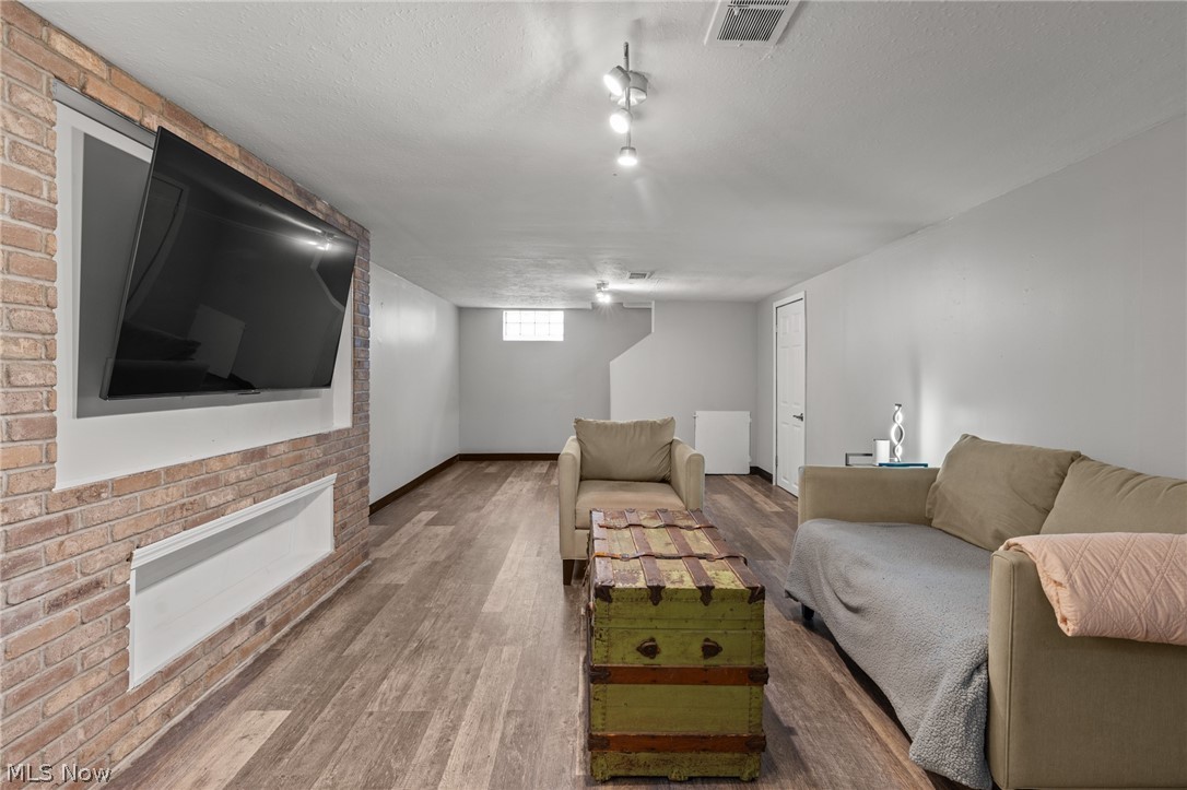 Living room with a brick fireplace, wall-mounted TV, beige sofas, and vintage green trunk coffee table.