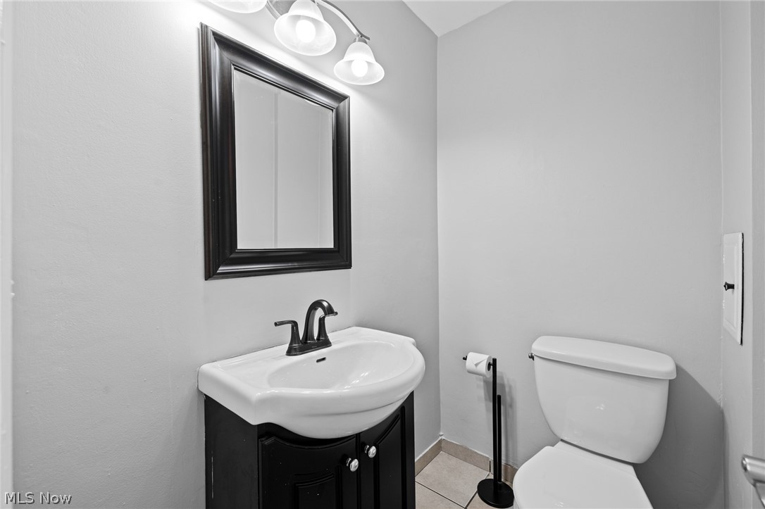 Bathroom with a white sink on a dark vanity, framed mirror, and toilet.