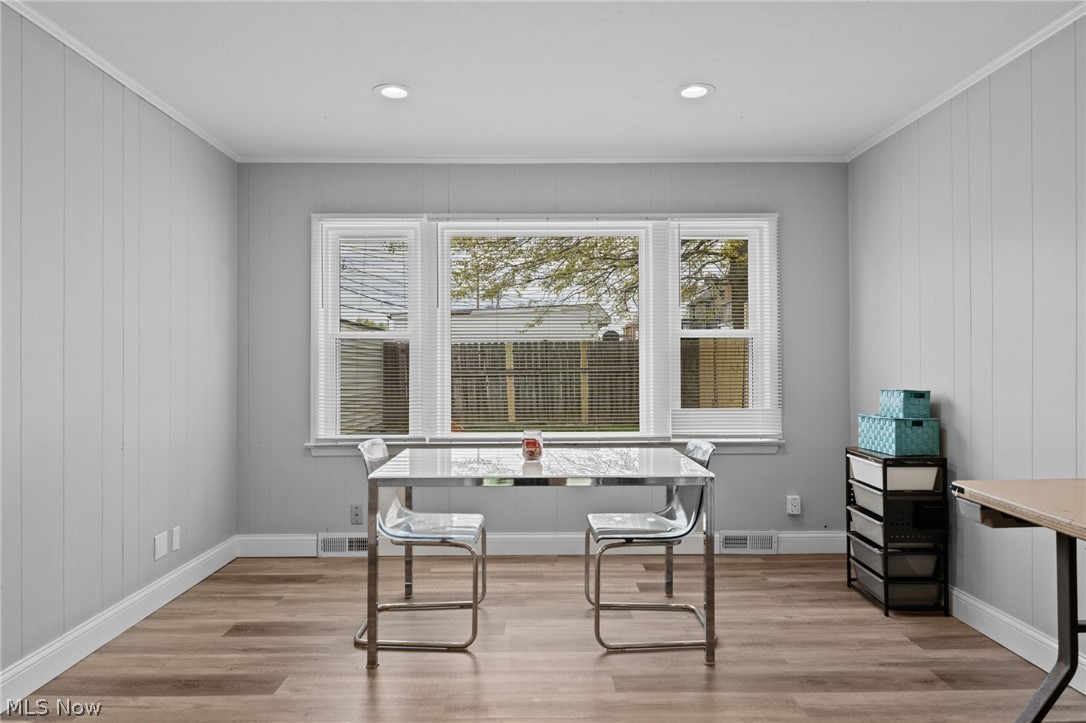 Bright room with a table and clear chairs beneath a large window with blinds.