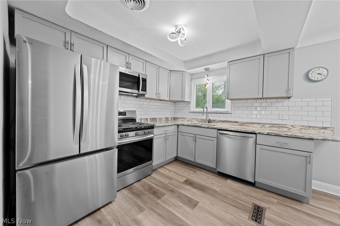 Kitchen with white cabinets, stainless steel appliances, granite counters, and a window above the sink.