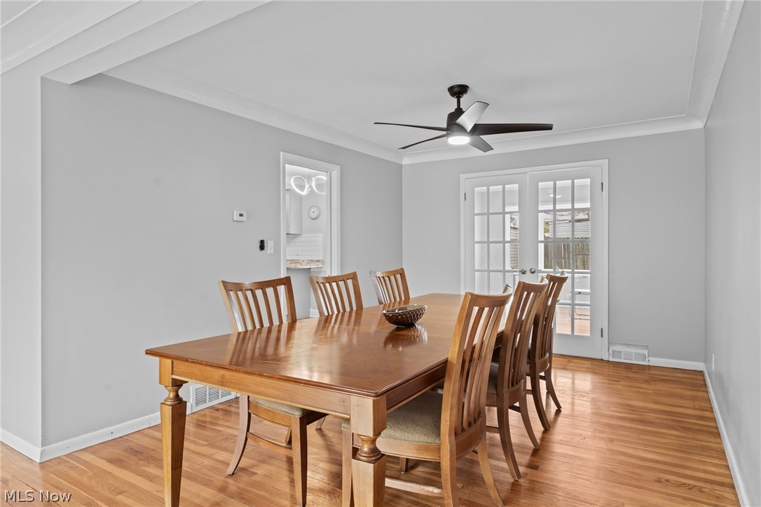 Dining room with a large wooden table, matching chairs, hardwood floors, and French doors.