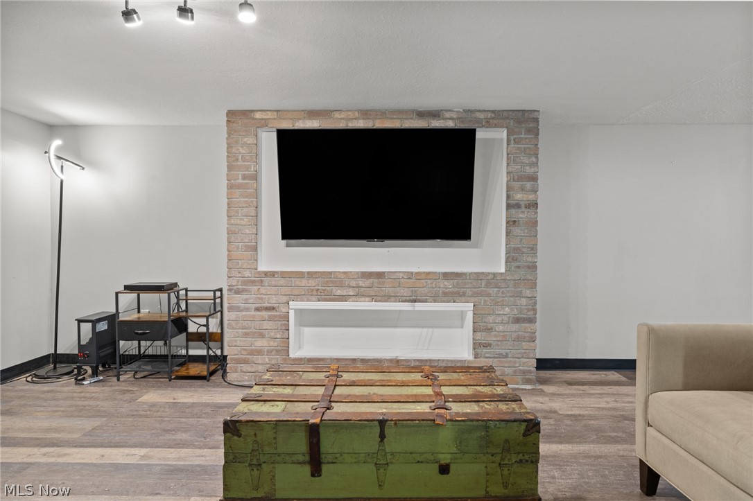 Living room with a brick fireplace, wall-mounted television, and green vintage trunk coffee table.