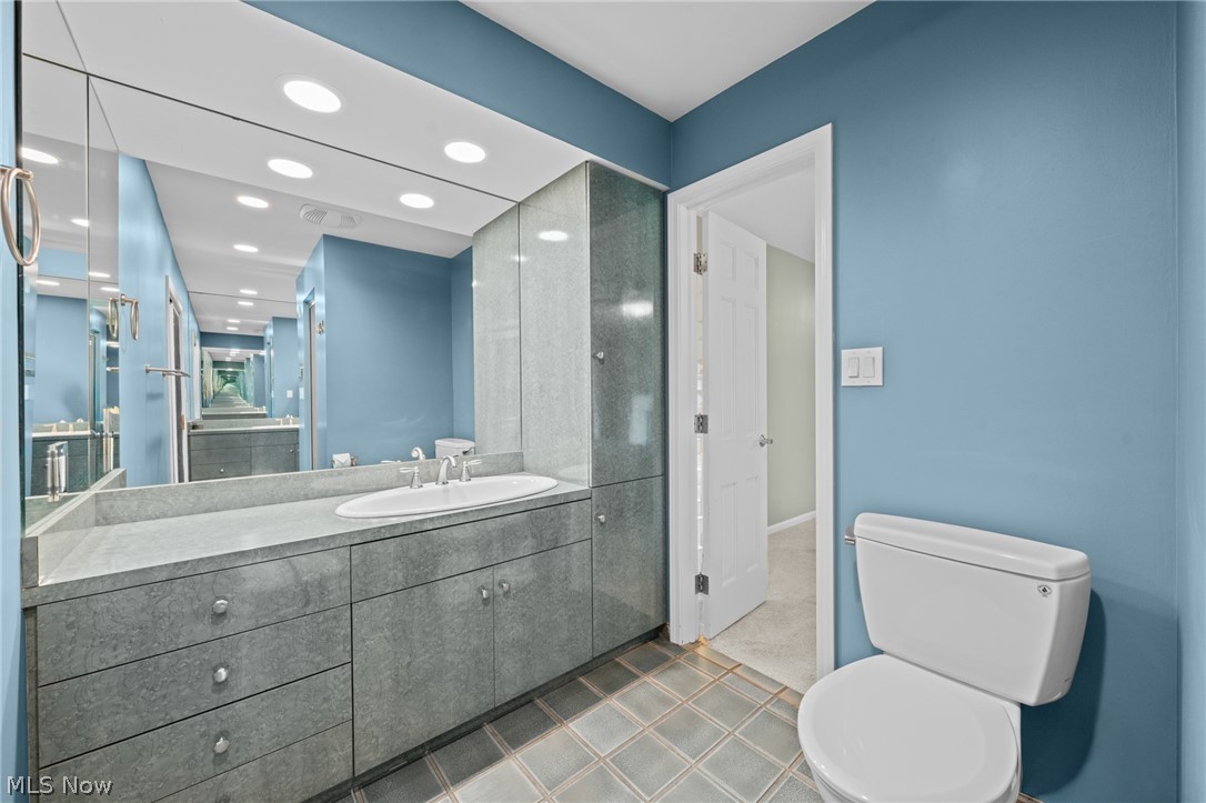 Bathroom with a long gray stone vanity, glass shower enclosure, and blue walls.