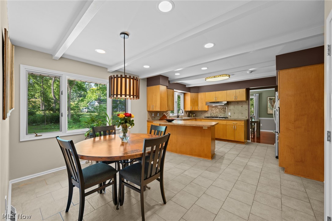 Kitchen and dining area with honey-colored cabinetry, a central island, and large garden-facing windows.