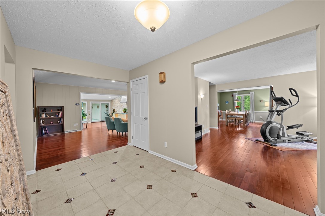 Open-plan home interior with tiled entry, hardwood floors, dining area, and exercise equipment.