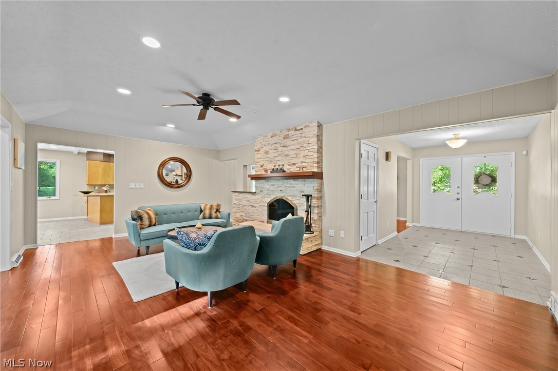 Living room with a stone fireplace, teal seating, and reddish hardwood floors.