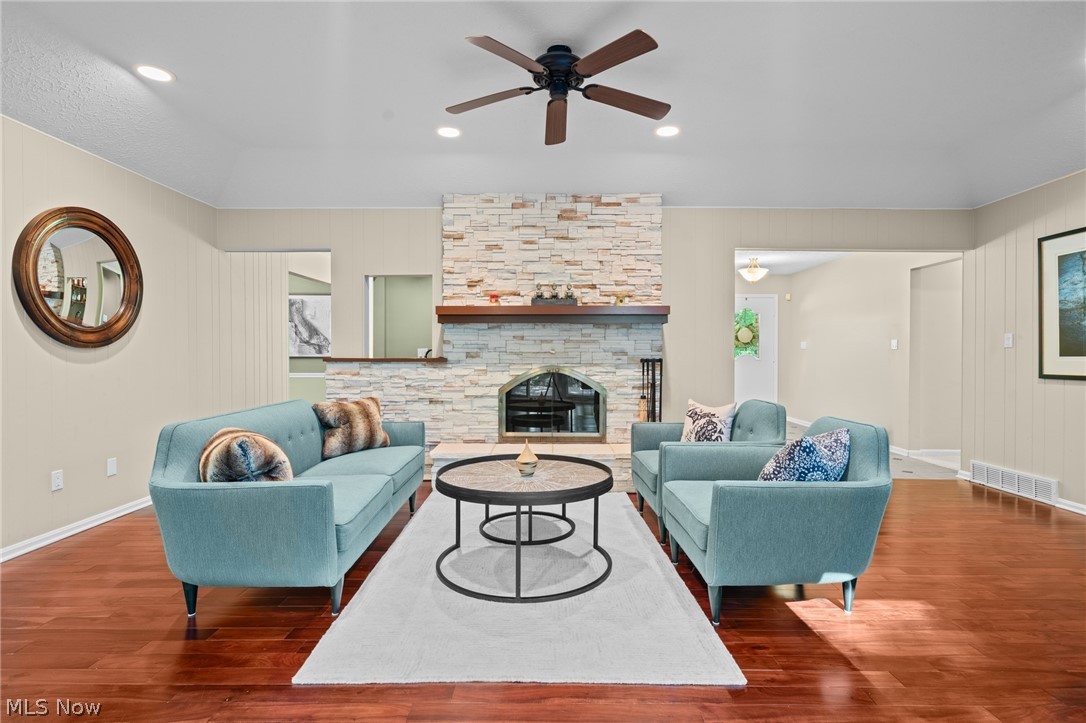 Living room with blue sofas, a stone fireplace, and polished hardwood floors.