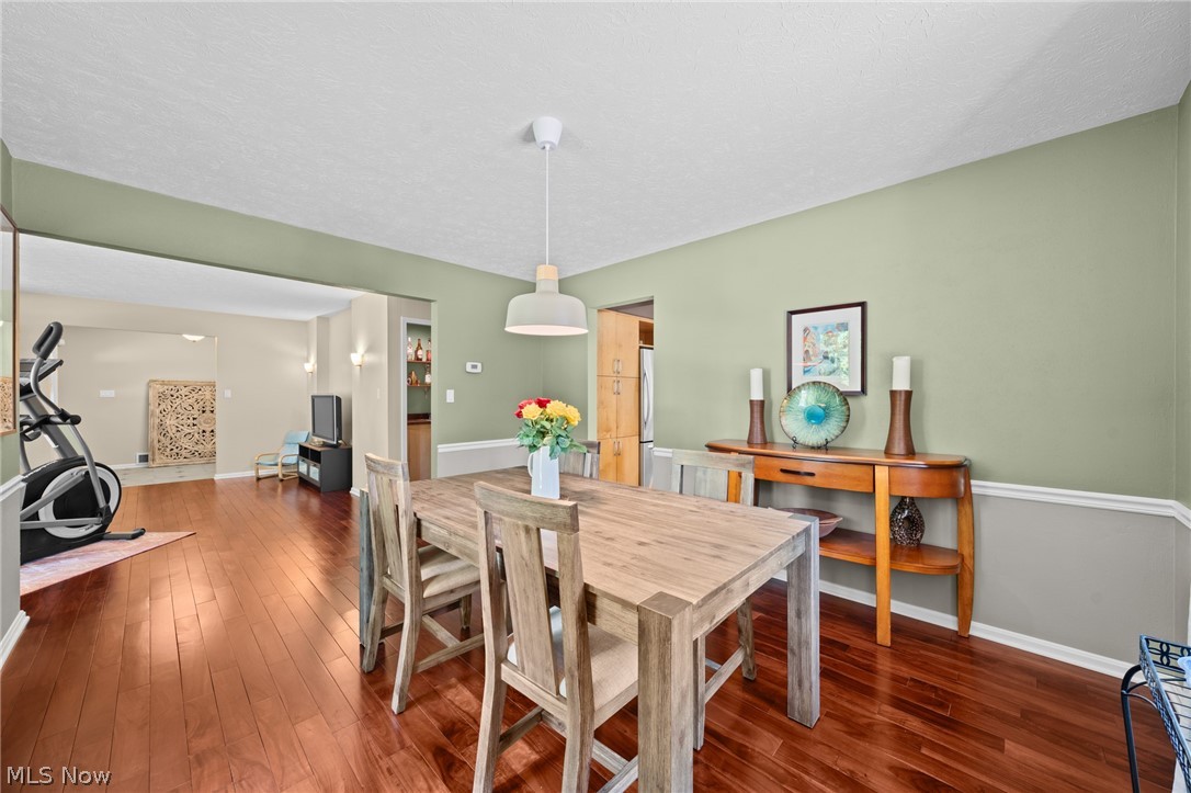 Dining room with a rustic wood table, sage green walls, and hardwood floors.