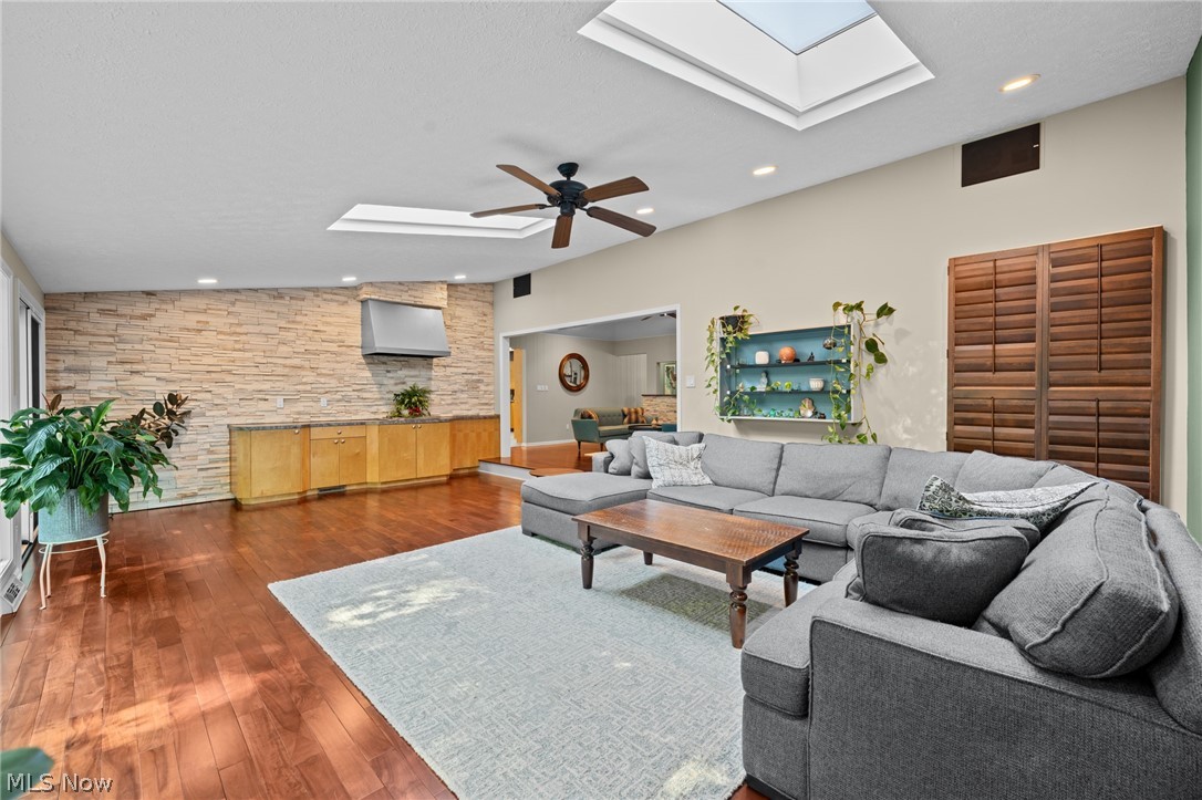 Living room with a gray sectional, stone accent wall, built-in counter, and skylights.