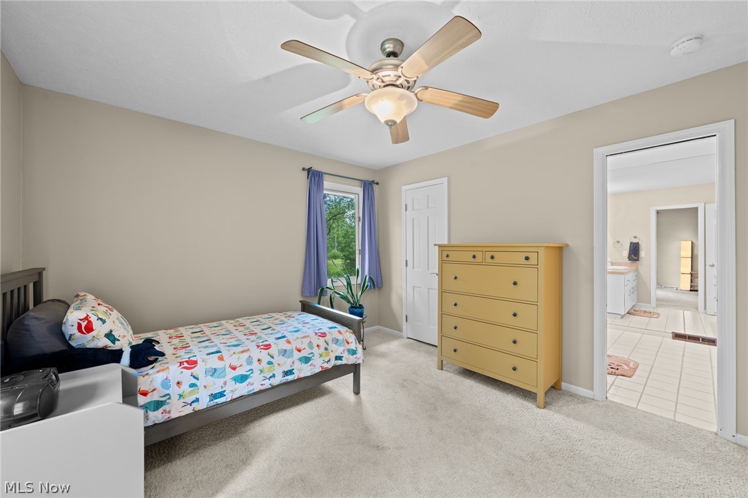 Bedroom with colorful fish-patterned bedding, a yellow dresser, and an adjoining tiled bathroom.